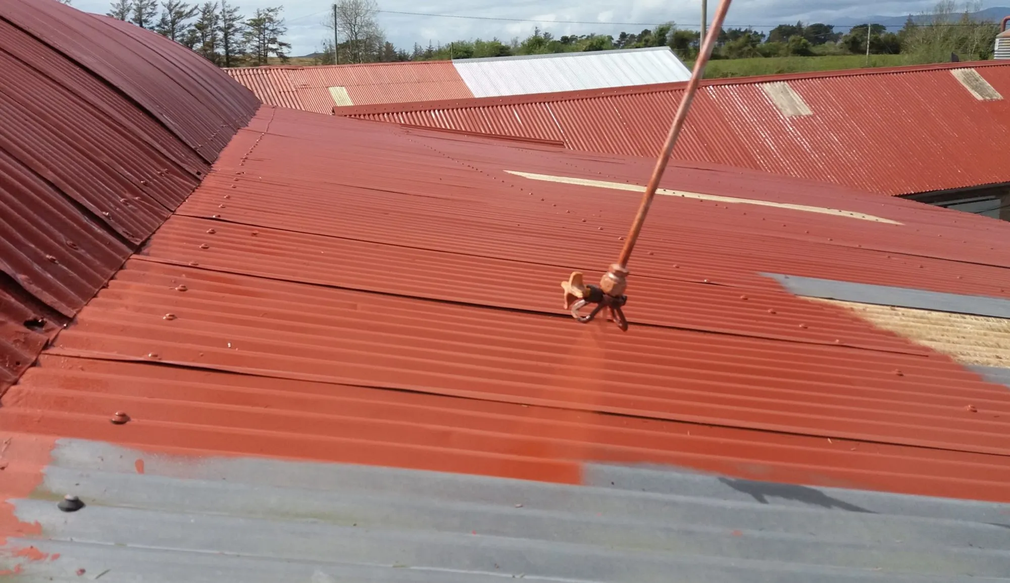 Corrugated farm roof being painted red